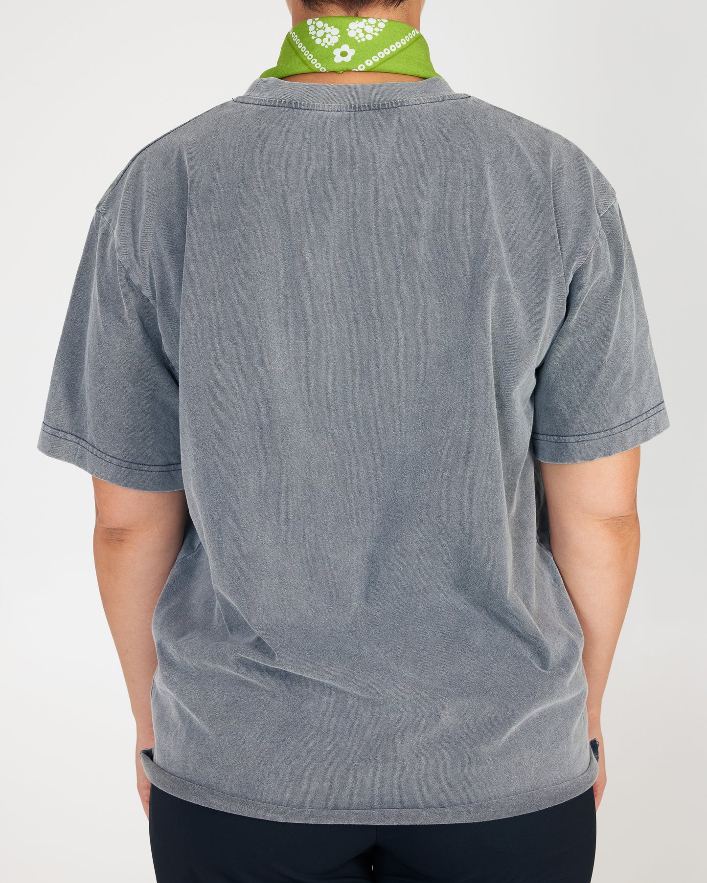 Person wearing a gray t-shirt with a green bandana around their neck on a white background