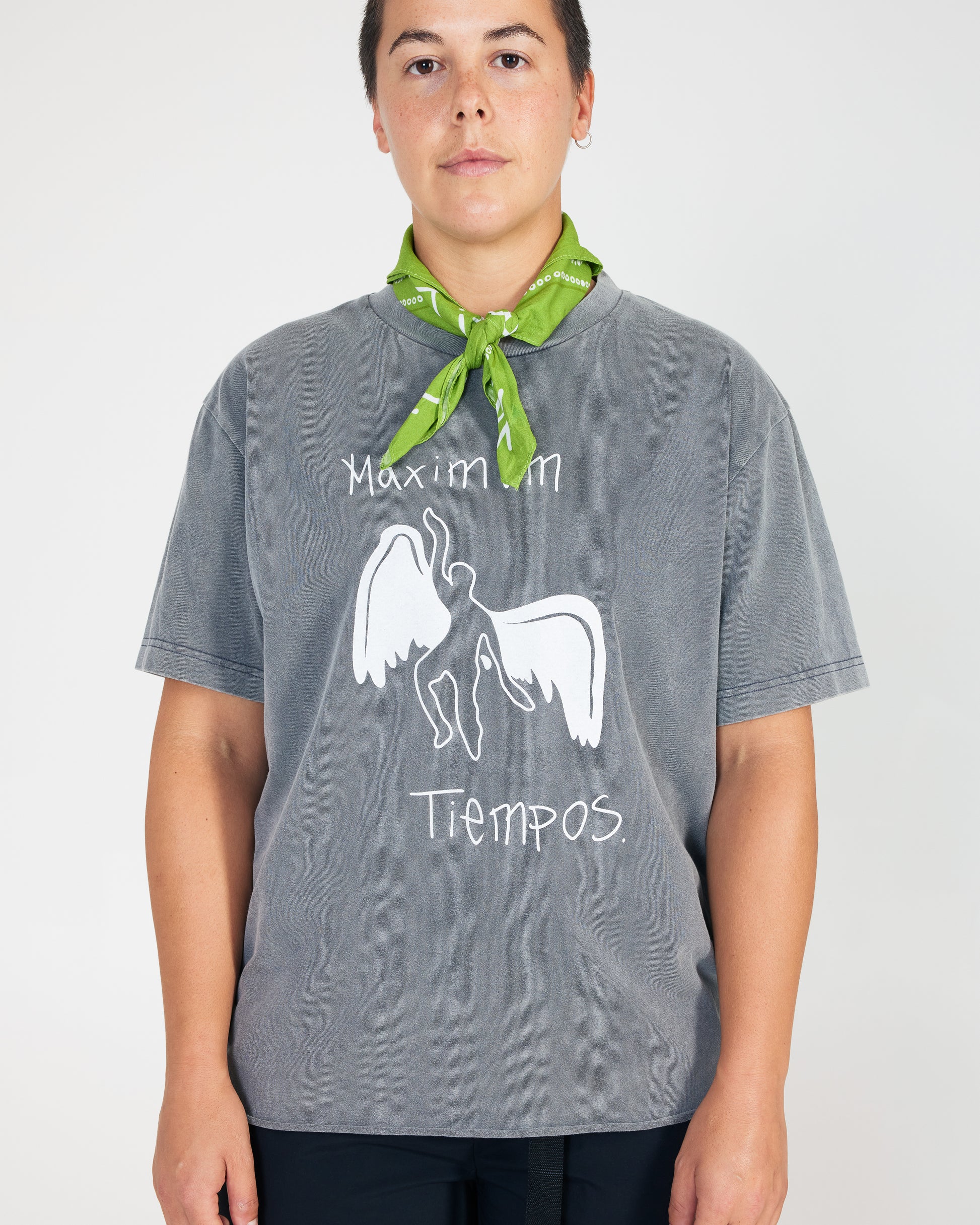 Person wearing a gray t-shirt with a graphic design and text, standing against a plain background