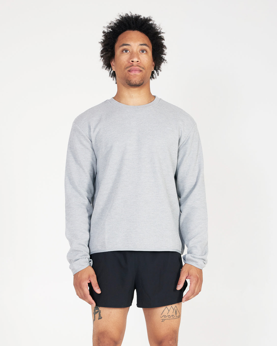 Man wearing a gray sweatshirt and black shorts on a white background