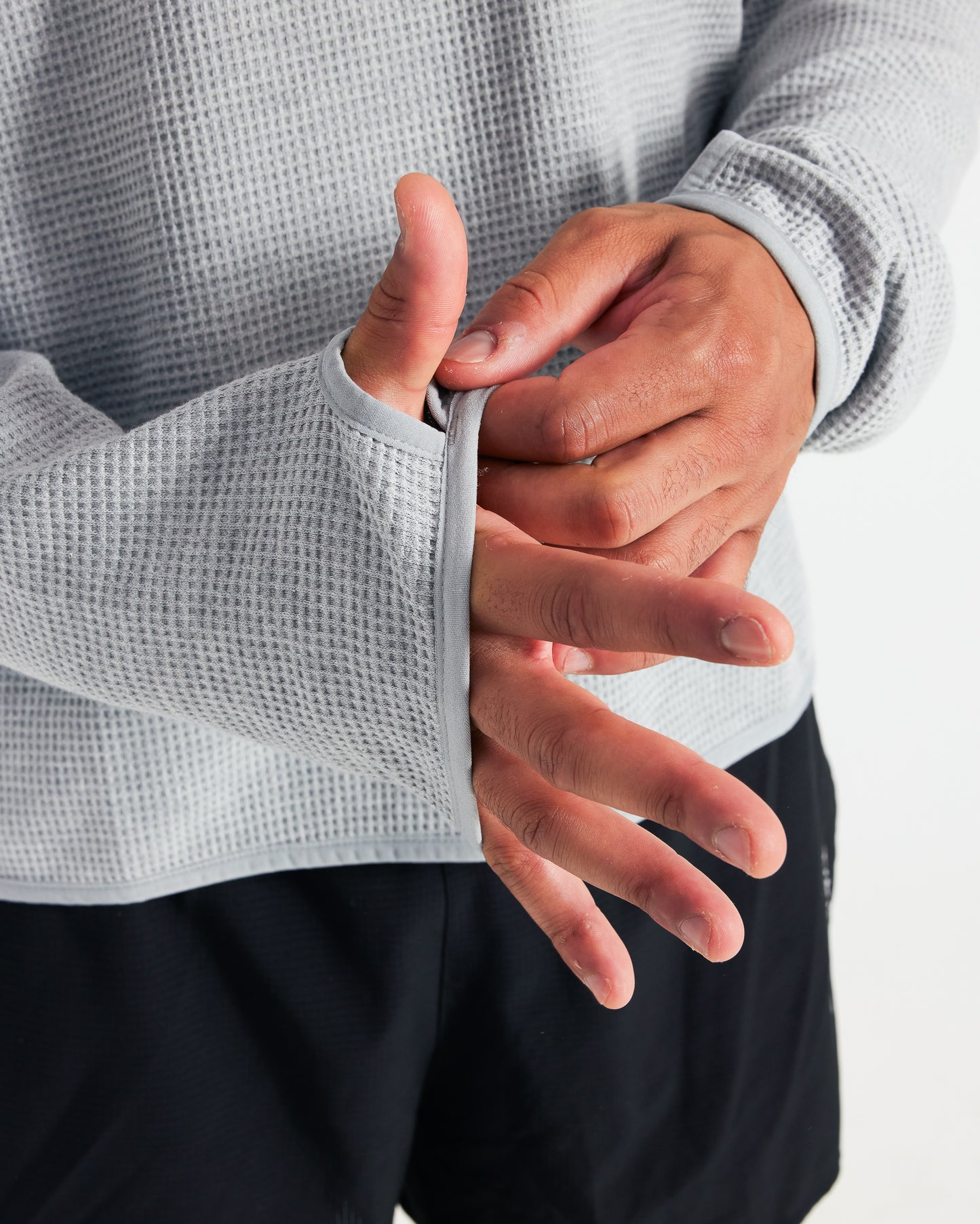 Person wearing a textured gray long-sleeve shirt with a close-up of their hand.