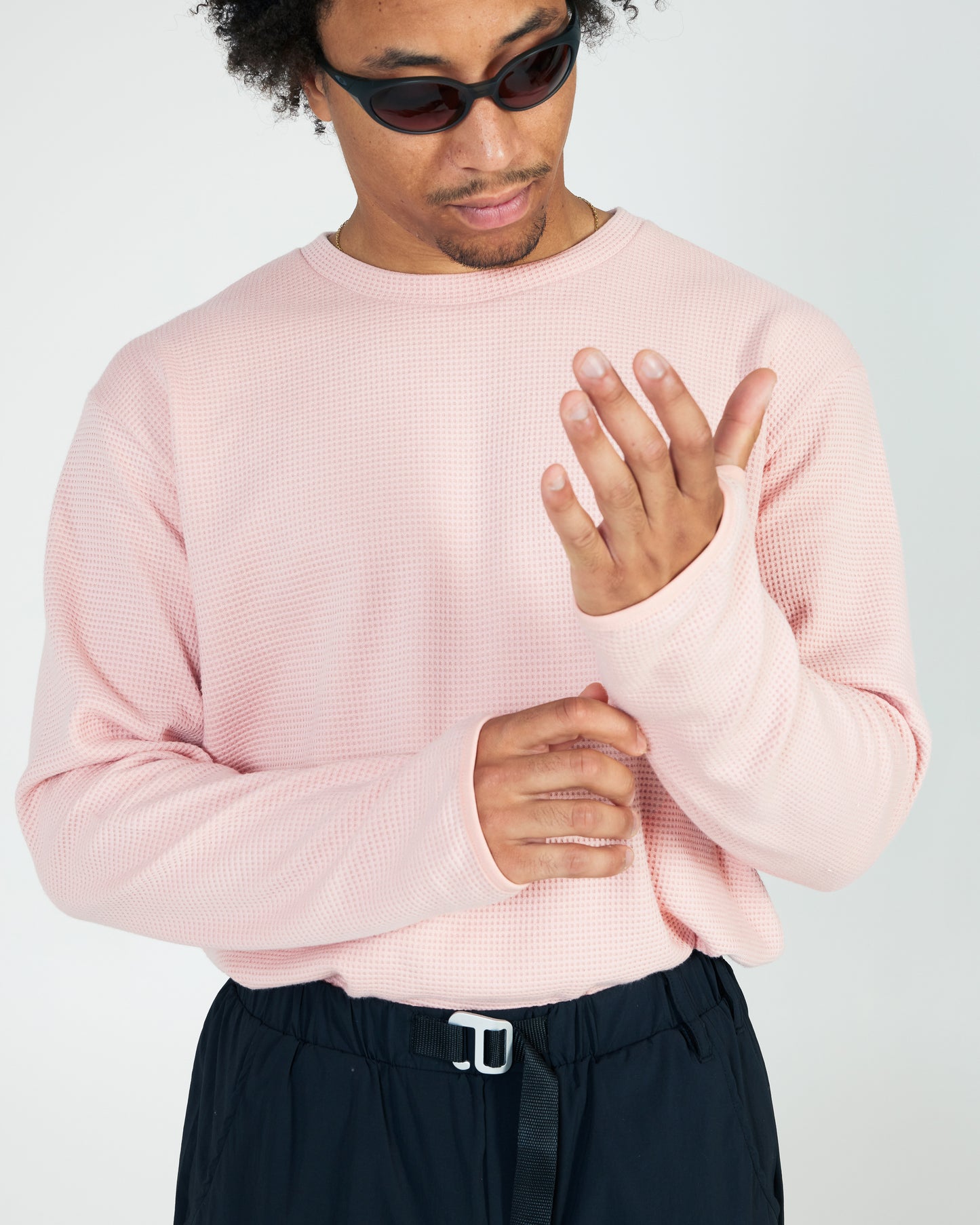 Person wearing a light pink sweater and dark pants on a plain background