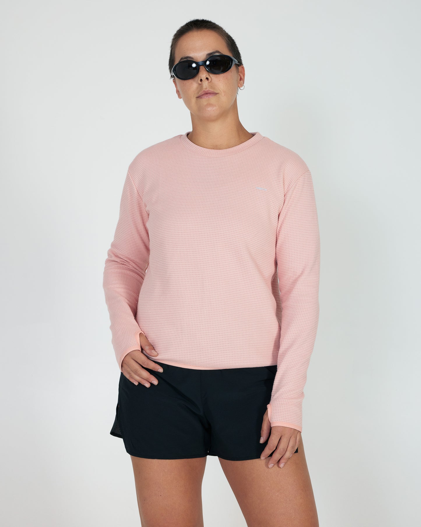 Person wearing a pink sweatshirt and black shorts on a white background