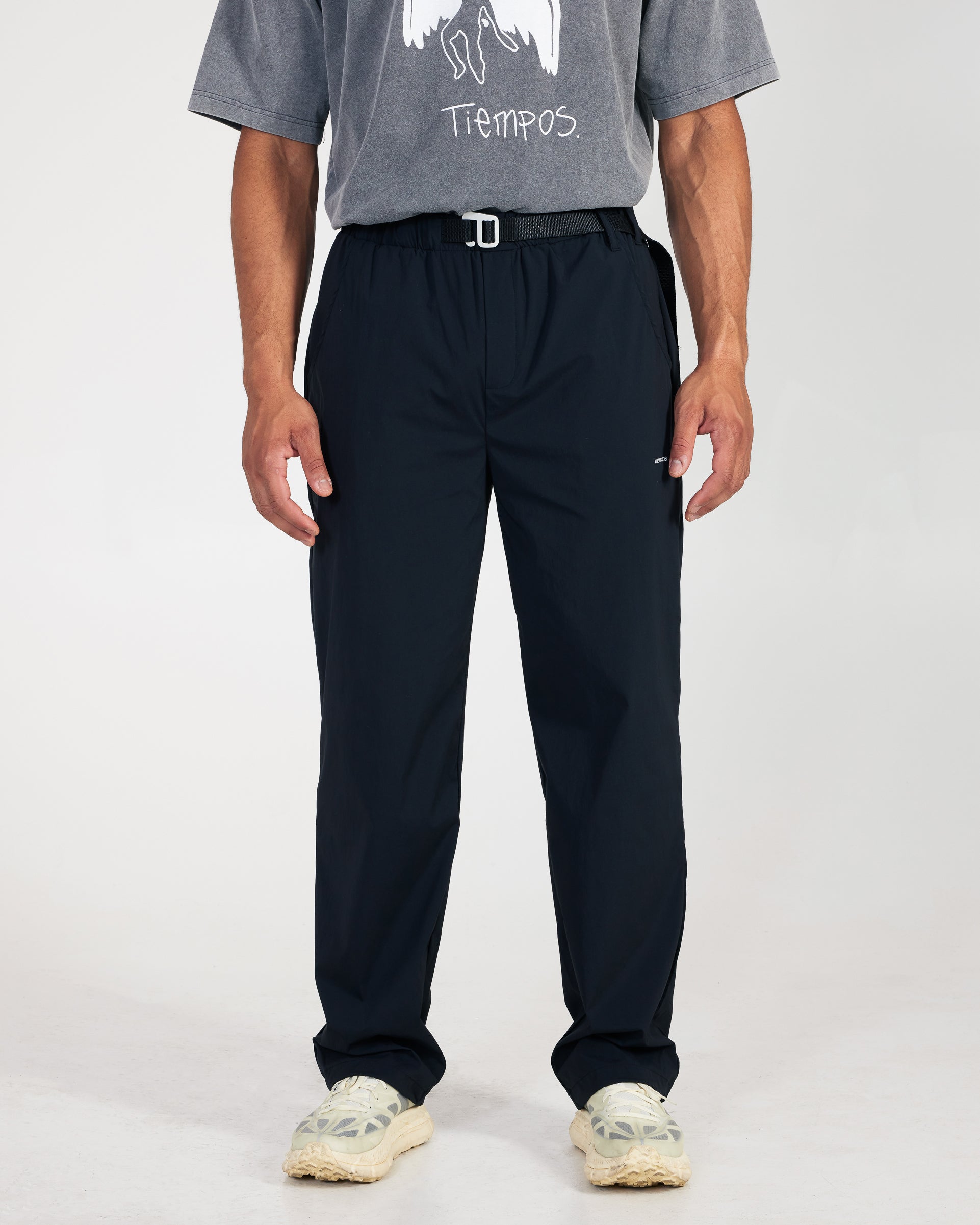 Person wearing a gray t-shirt with text and dark pants on a white background