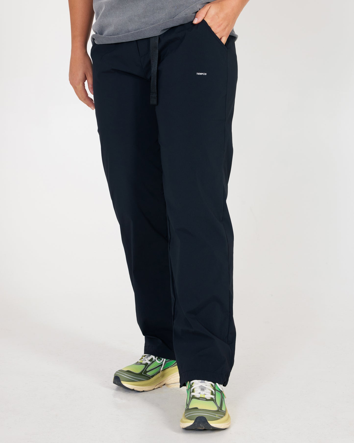 Person wearing black pants with a small logo on a white background