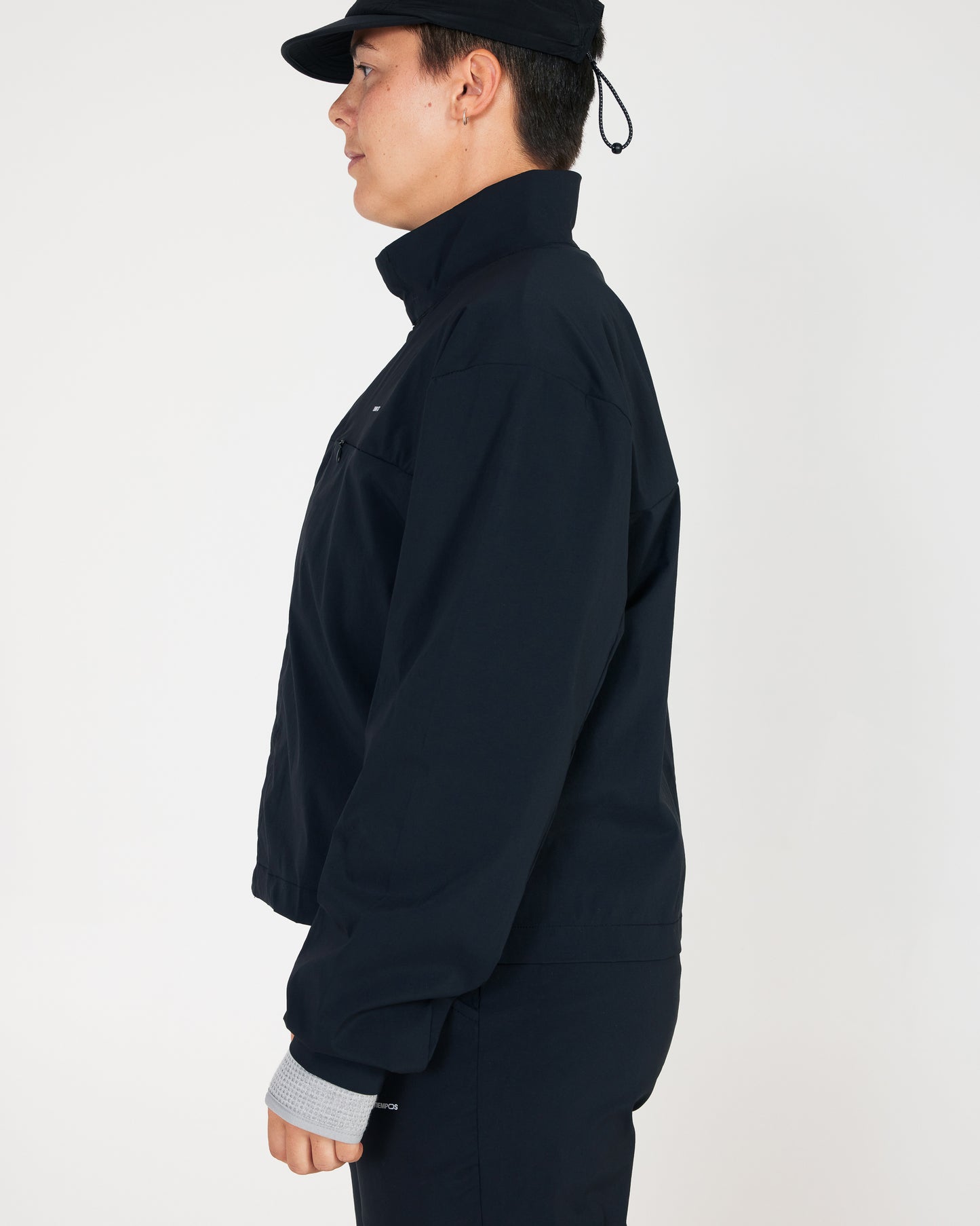 Person wearing a dark jacket and cap on a plain background