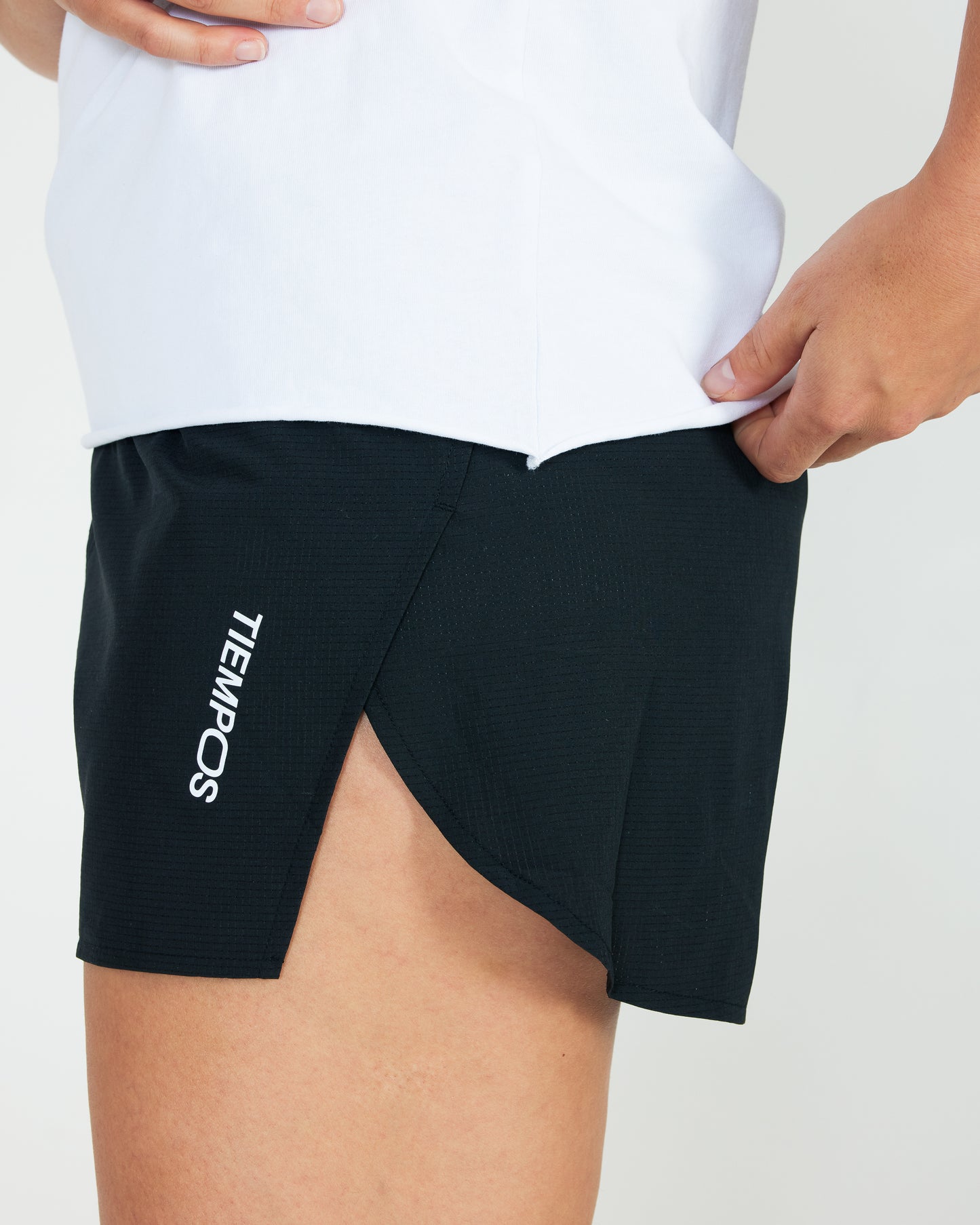 Black athletic shorts with 'Tiempo' branding worn by a person on a light gray background