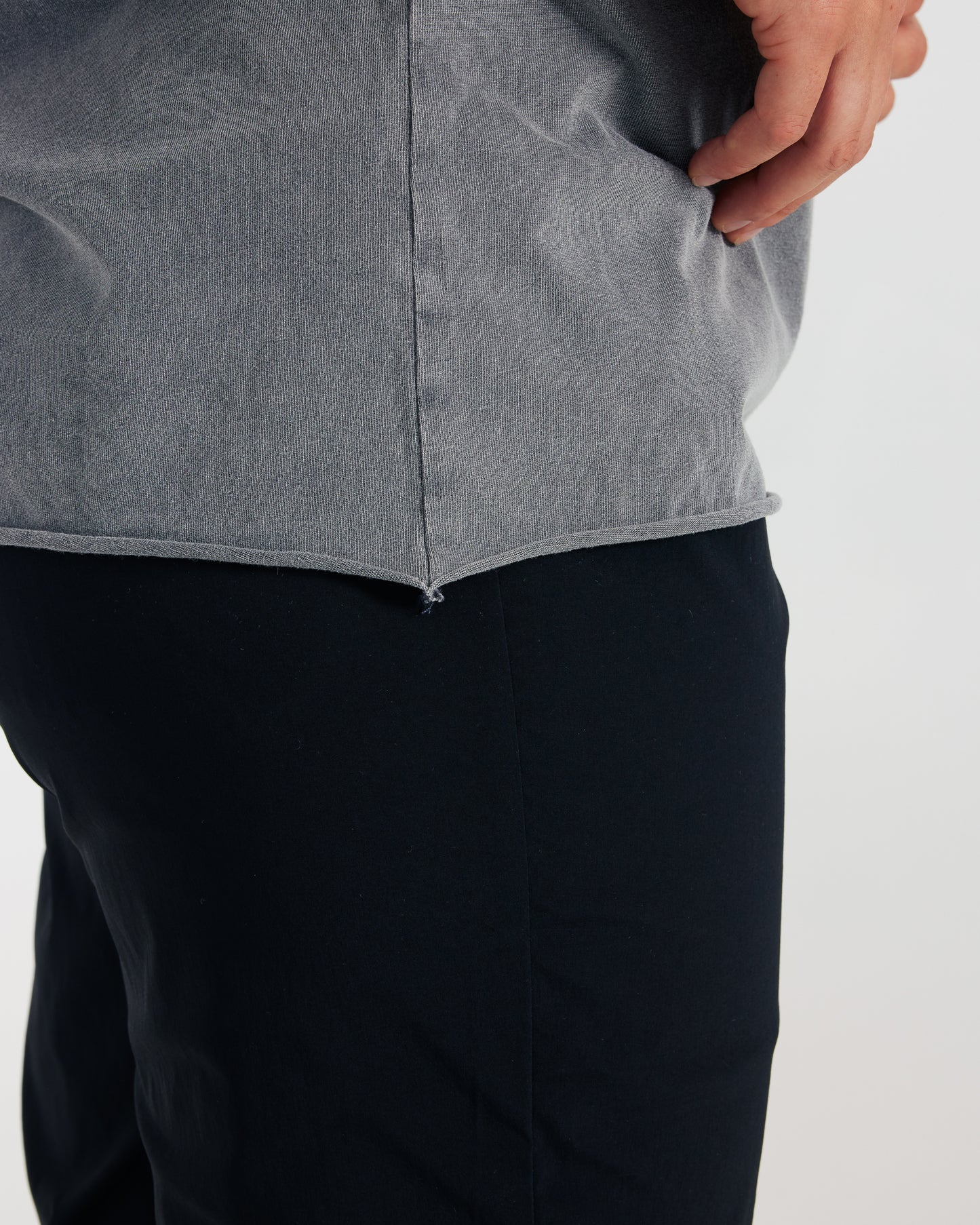 Person wearing a gray jacket and black pants on a light gray background