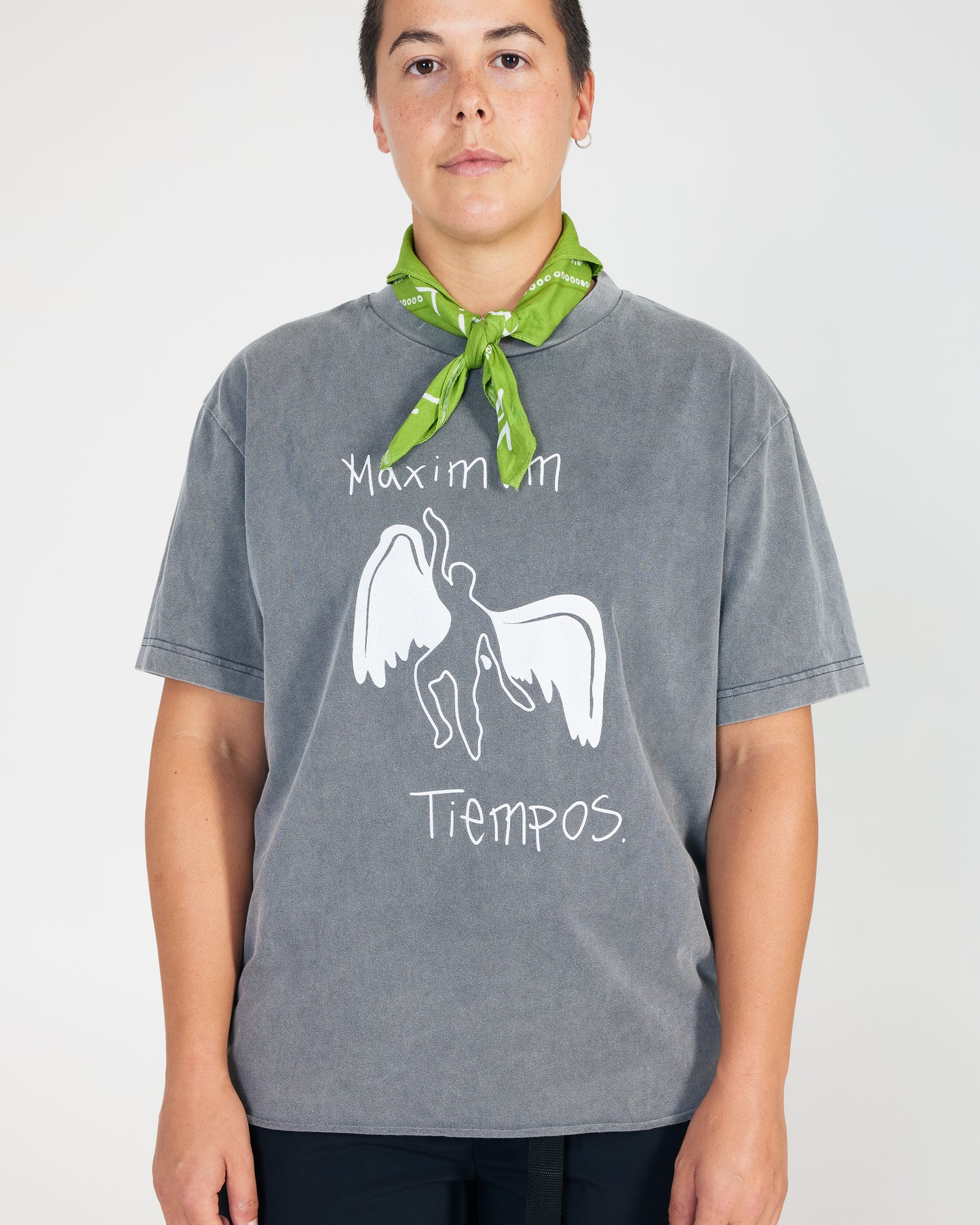 Person wearing a gray t-shirt with a graphic design and text, standing against a plain background