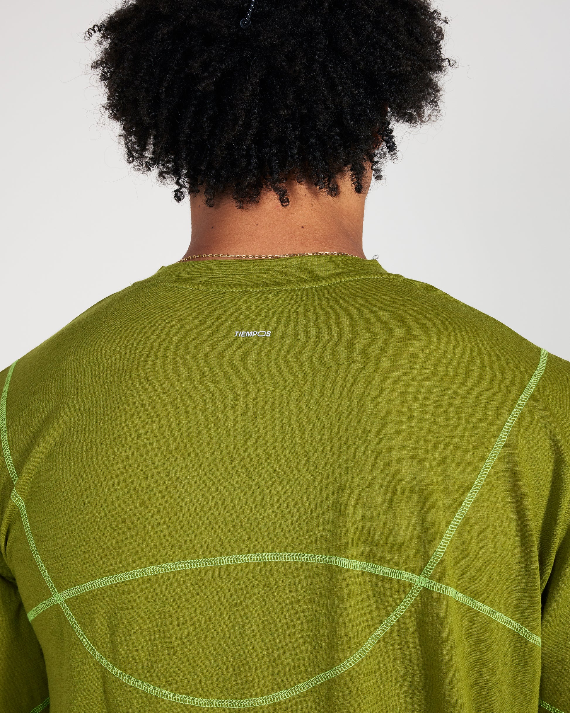 Person wearing a green athletic shirt with a brand logo on the back against a white background