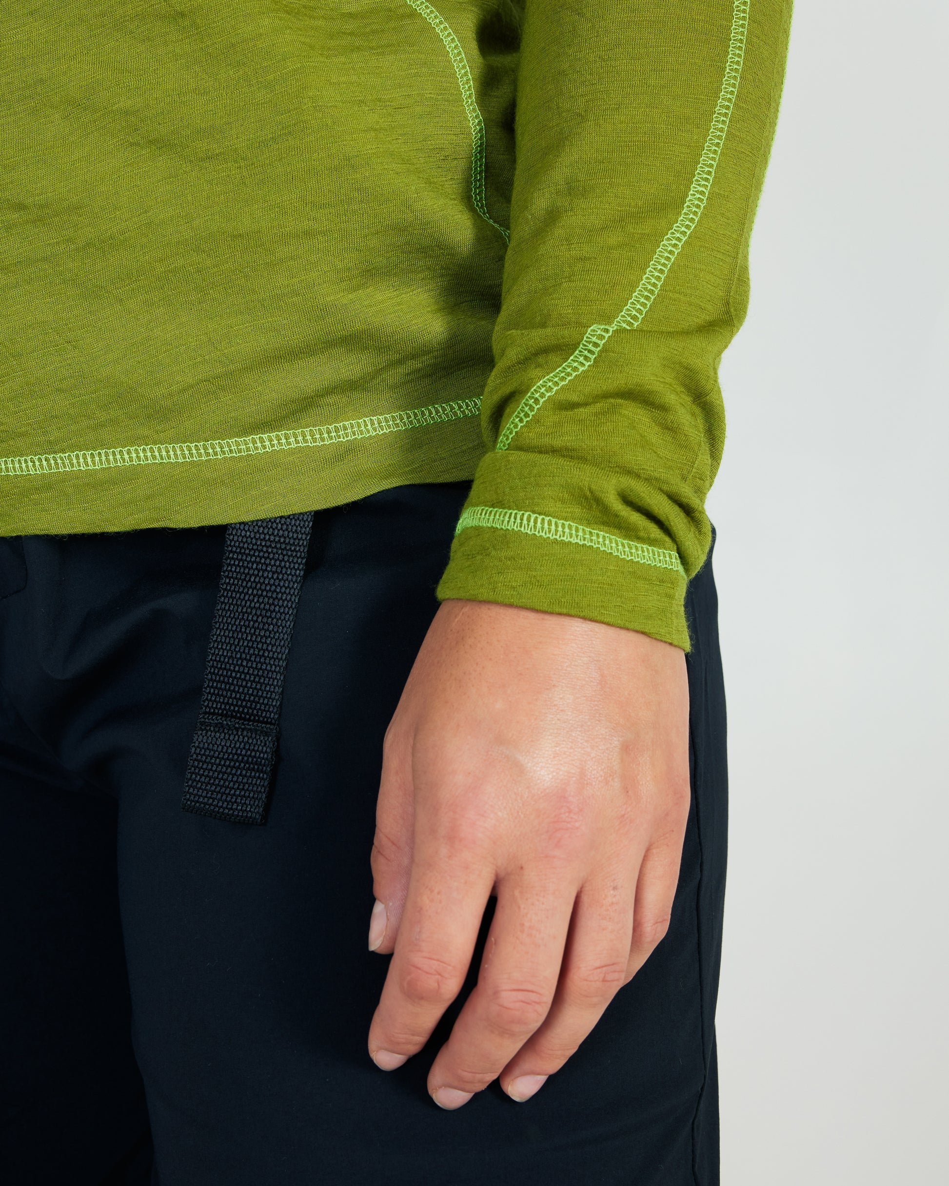 Green long-sleeve shirt with white stitching on a plain background