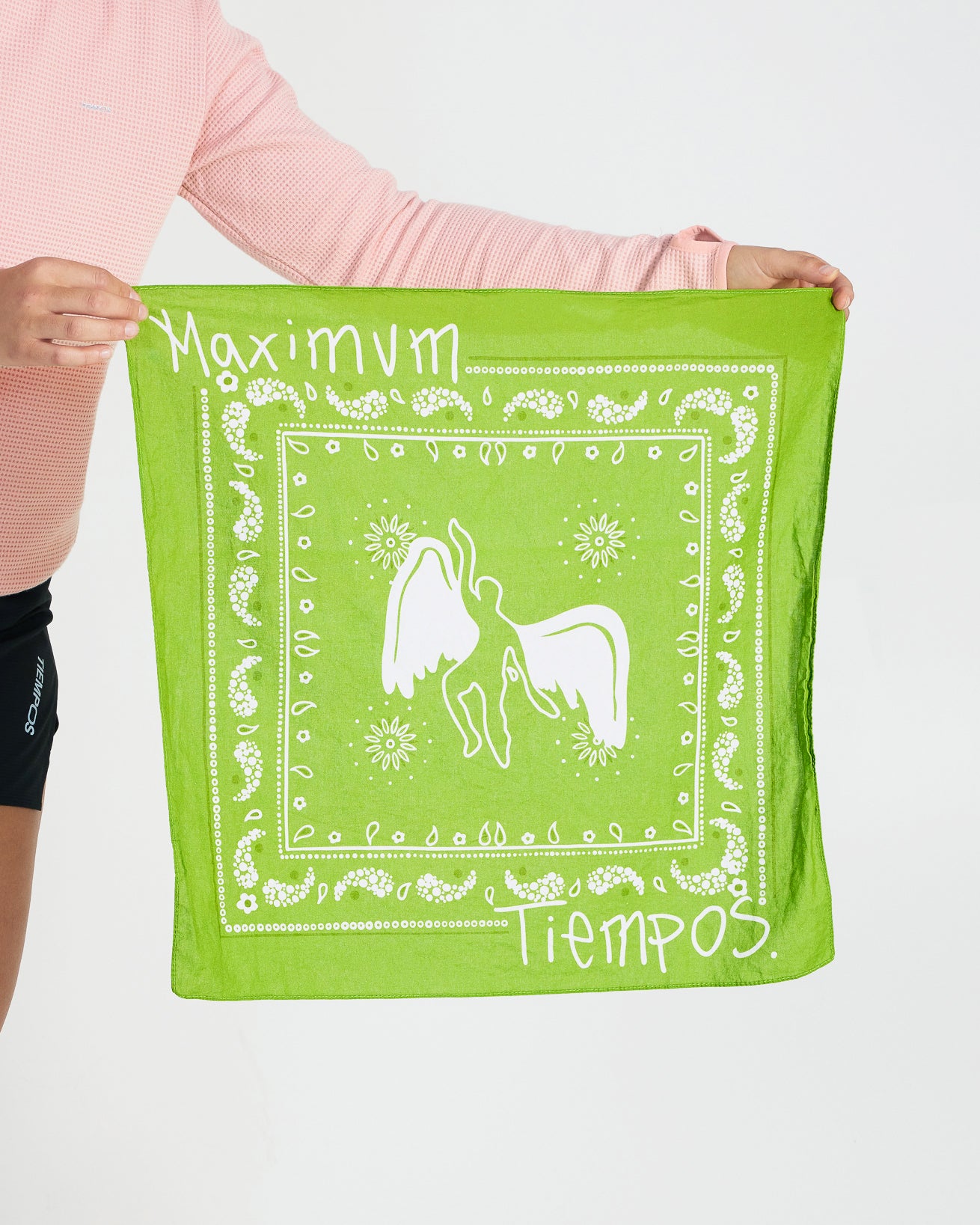 Person holding a green bandana with white designs and text.