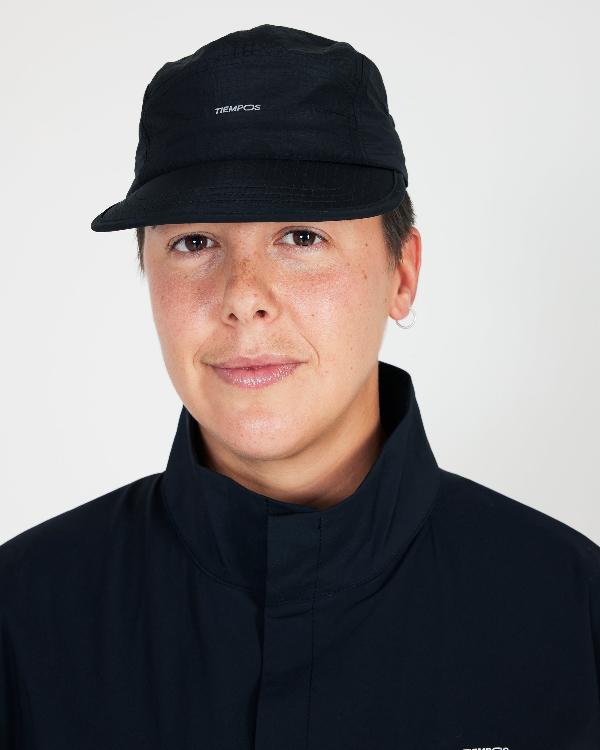 Person wearing a black cap and dark jacket on a white background