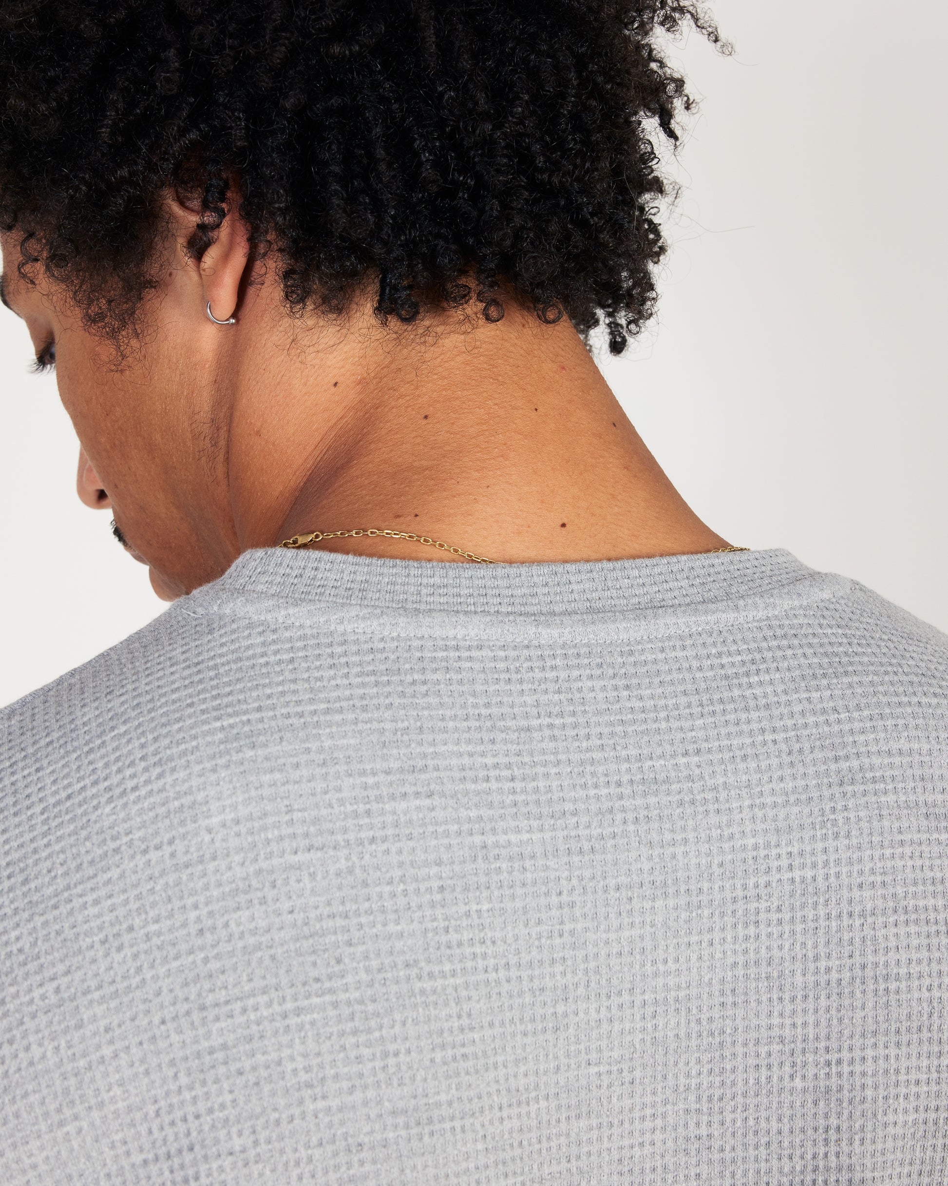 Person wearing a textured gray sweater with a plain background