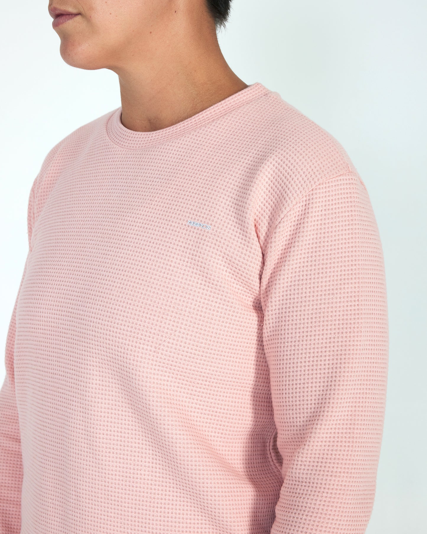 Person wearing a pink textured long-sleeve shirt against a light background