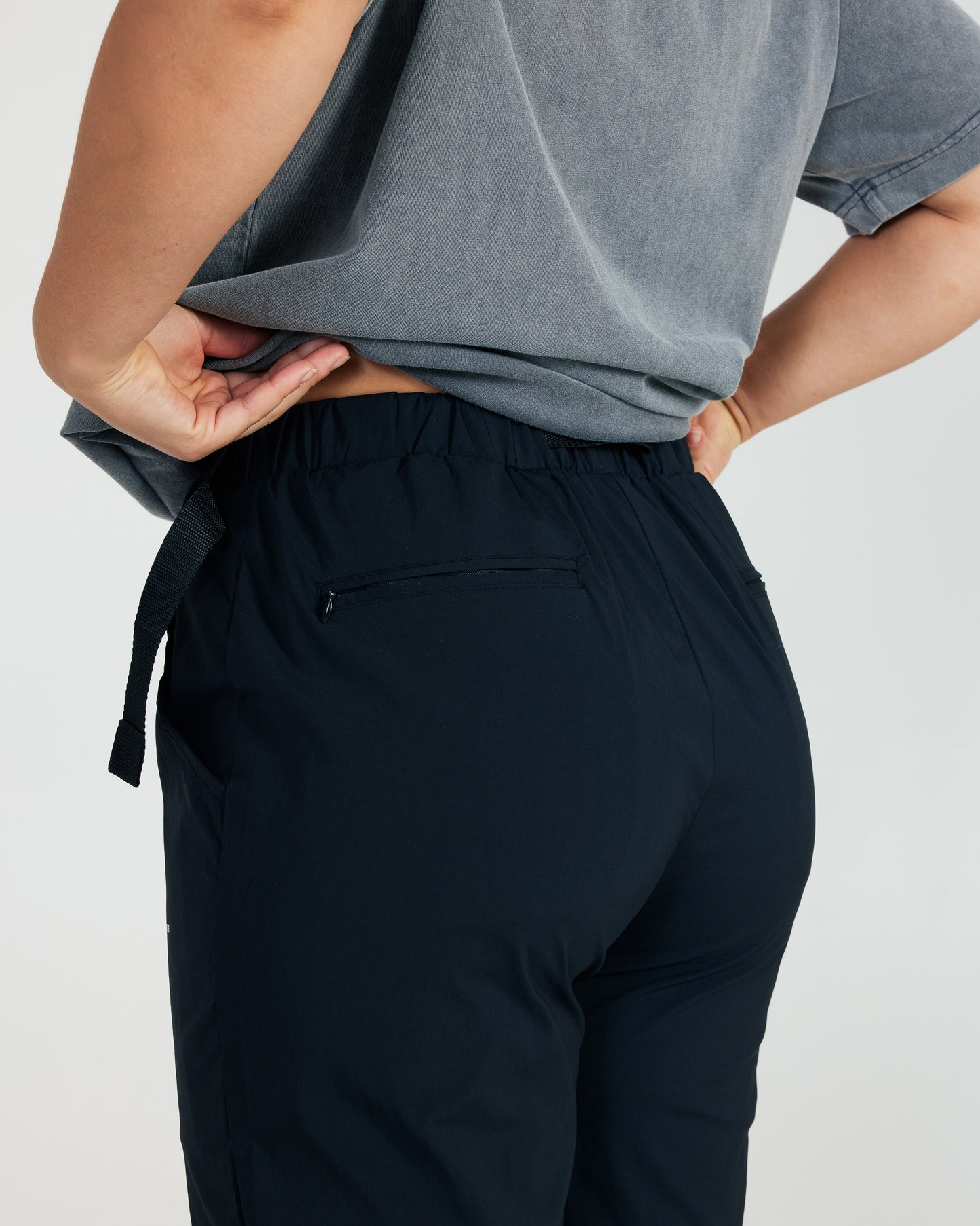 Person wearing black pants and a gray top on a plain background