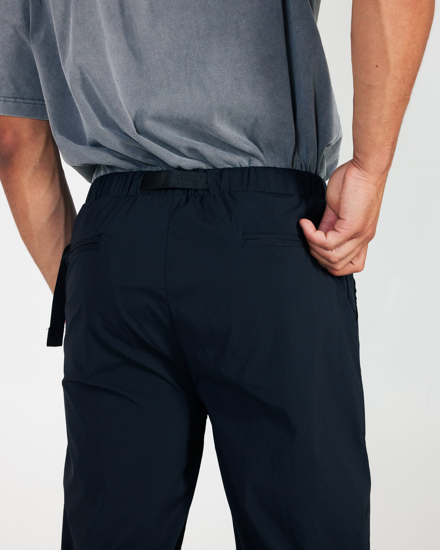 Person wearing black pants and a gray shirt on a white background