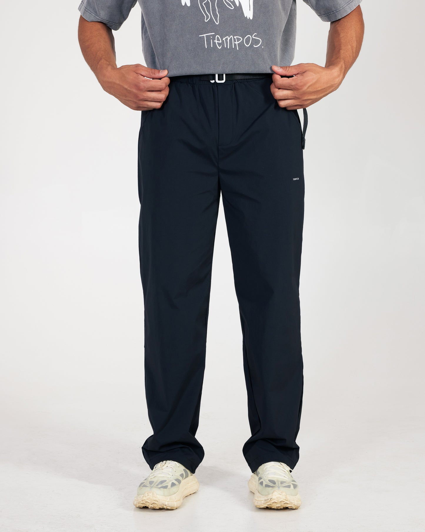 Person wearing black pants and a gray shirt with text on a white background