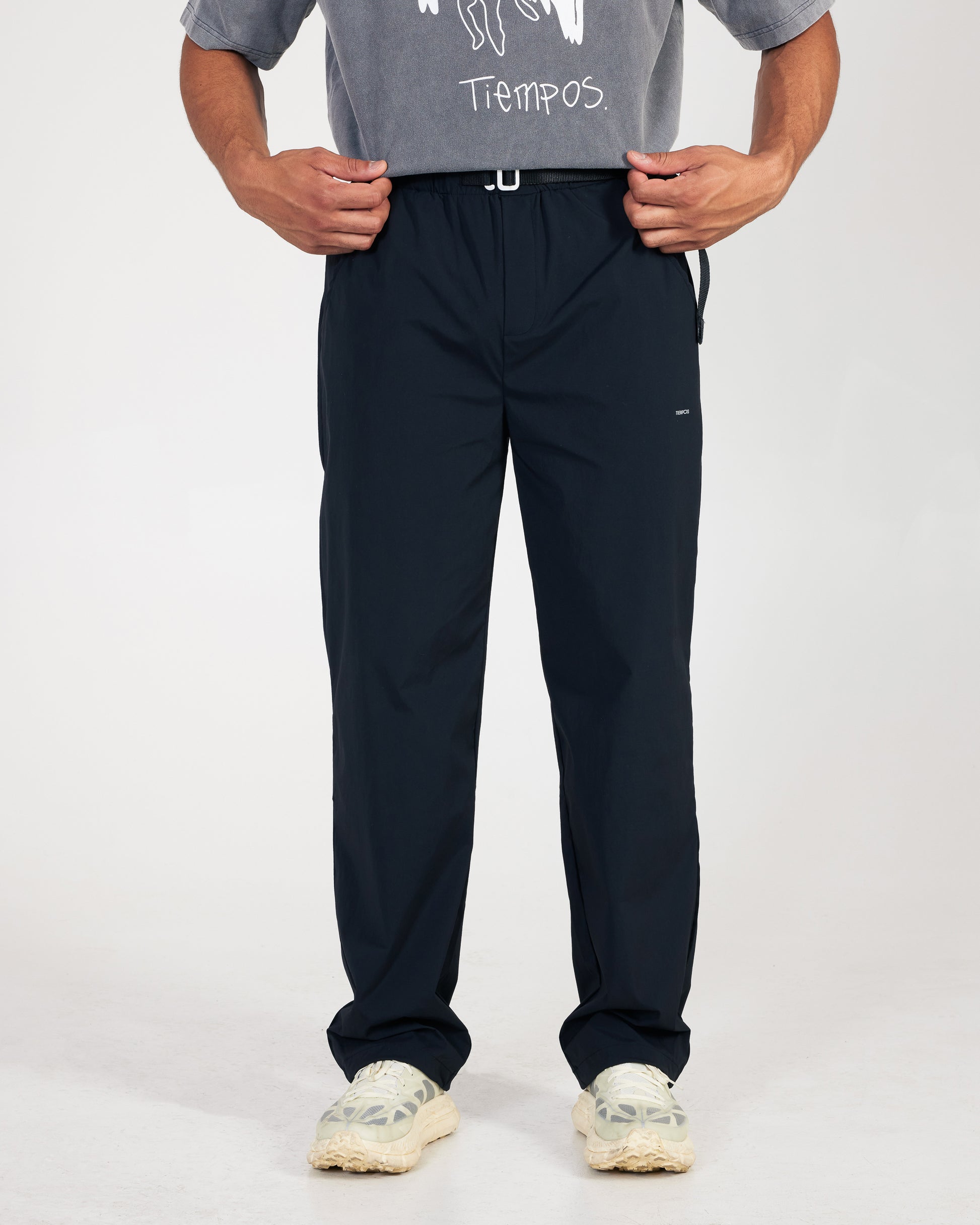 Person wearing black pants and a gray shirt with text on a white background