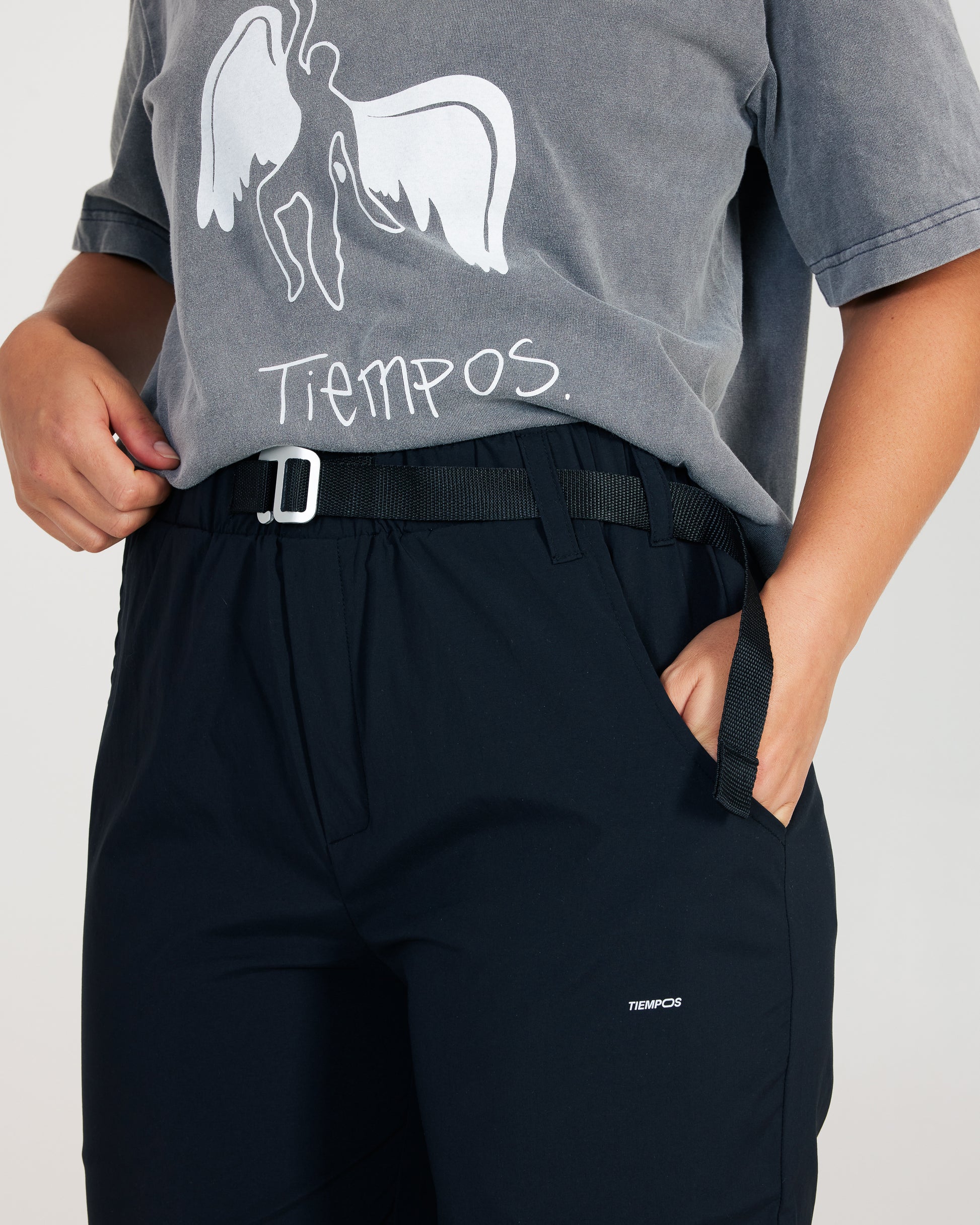 Person wearing a gray t-shirt with a graphic design and black pants on a light gray background