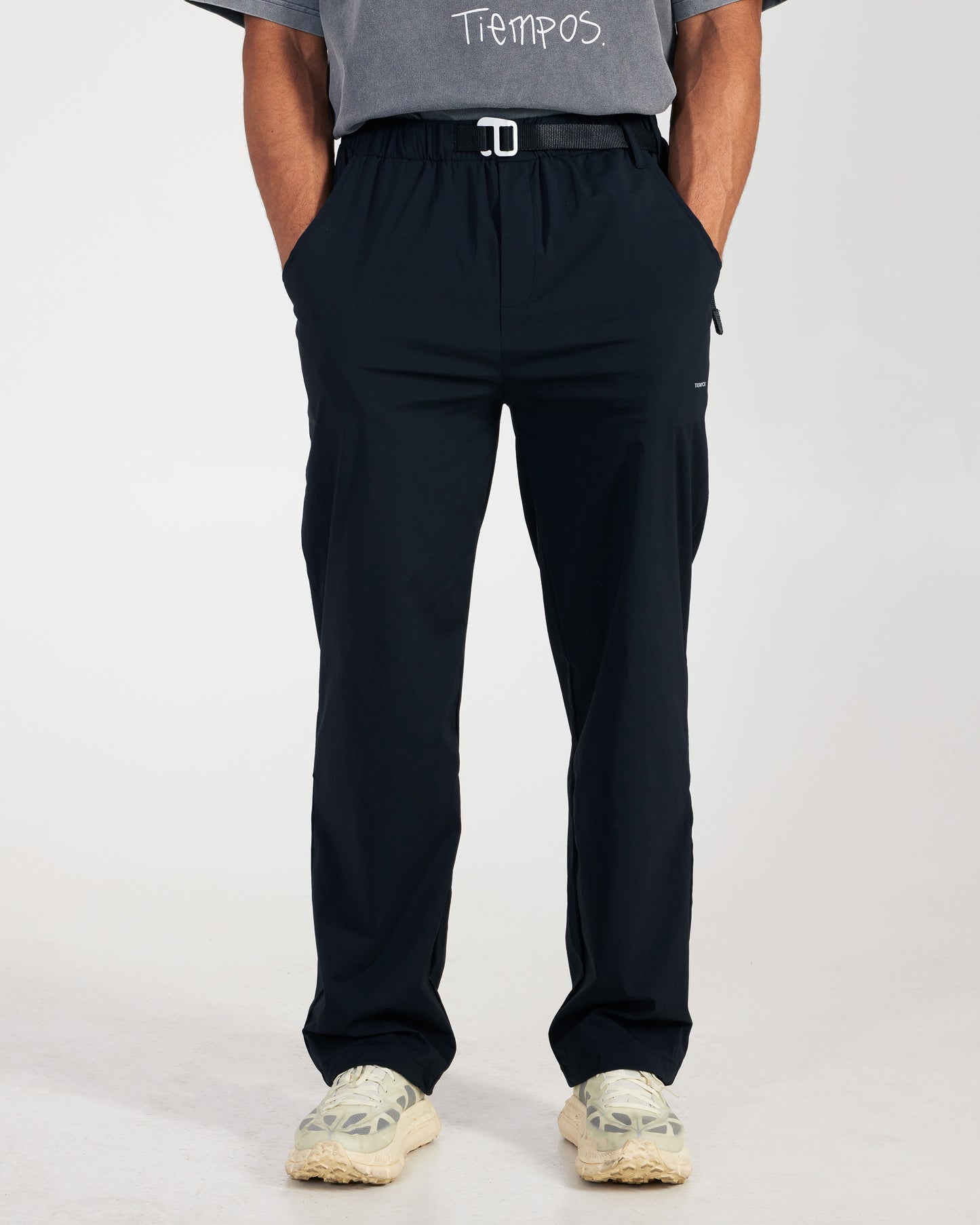 Person wearing navy pants and a gray shirt with 'Tiempos' branding on a white background