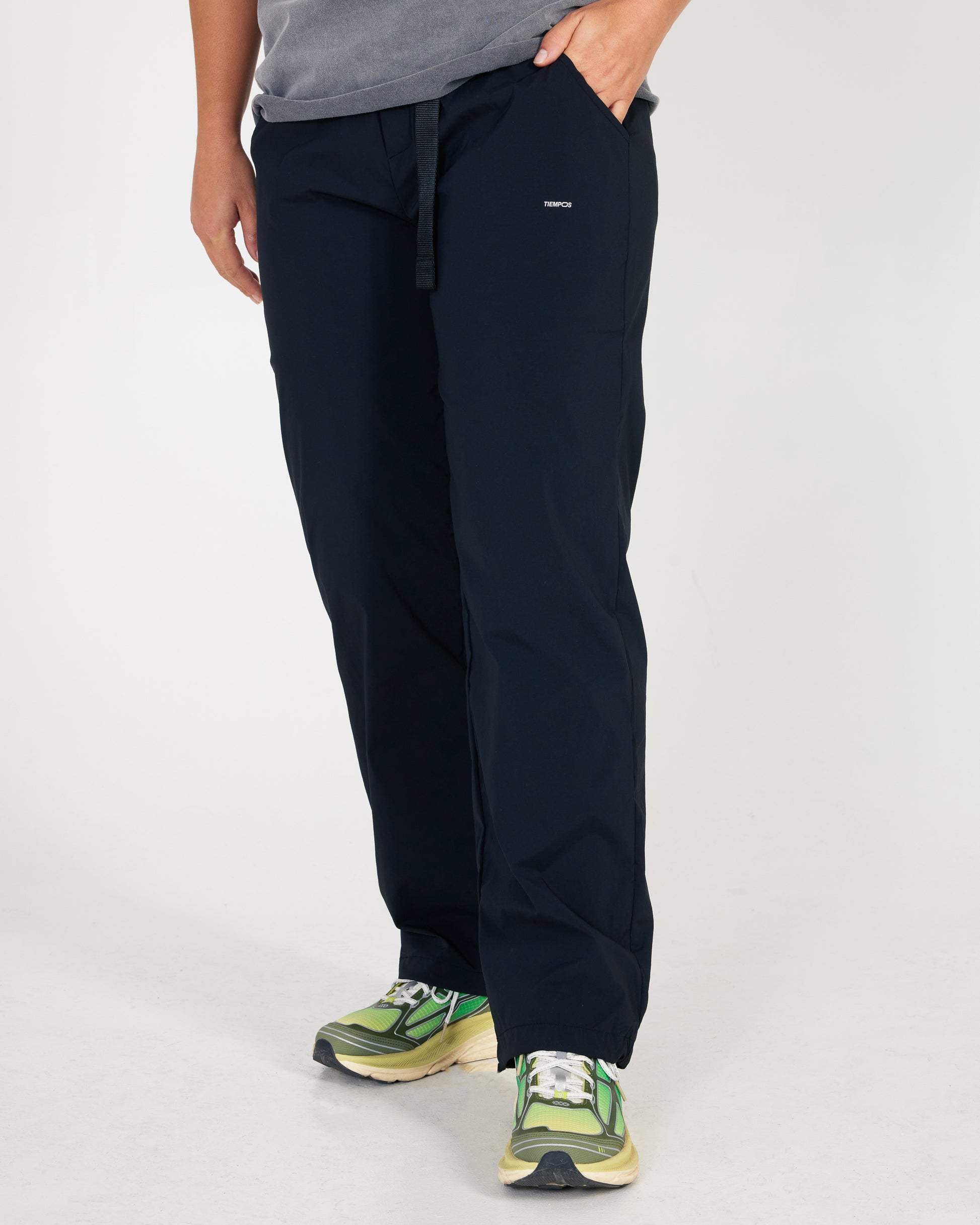 Person wearing black pants with a small logo on a white background