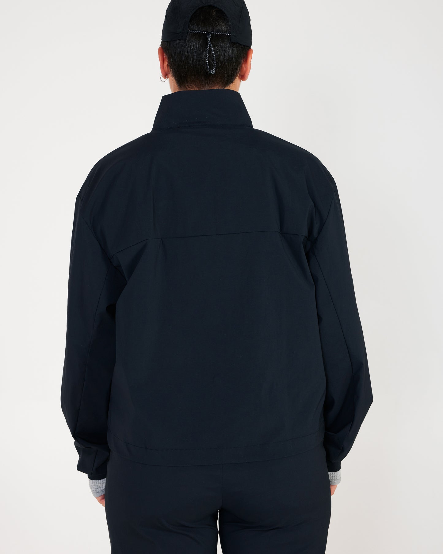 Person wearing a black jacket and pants on a white background