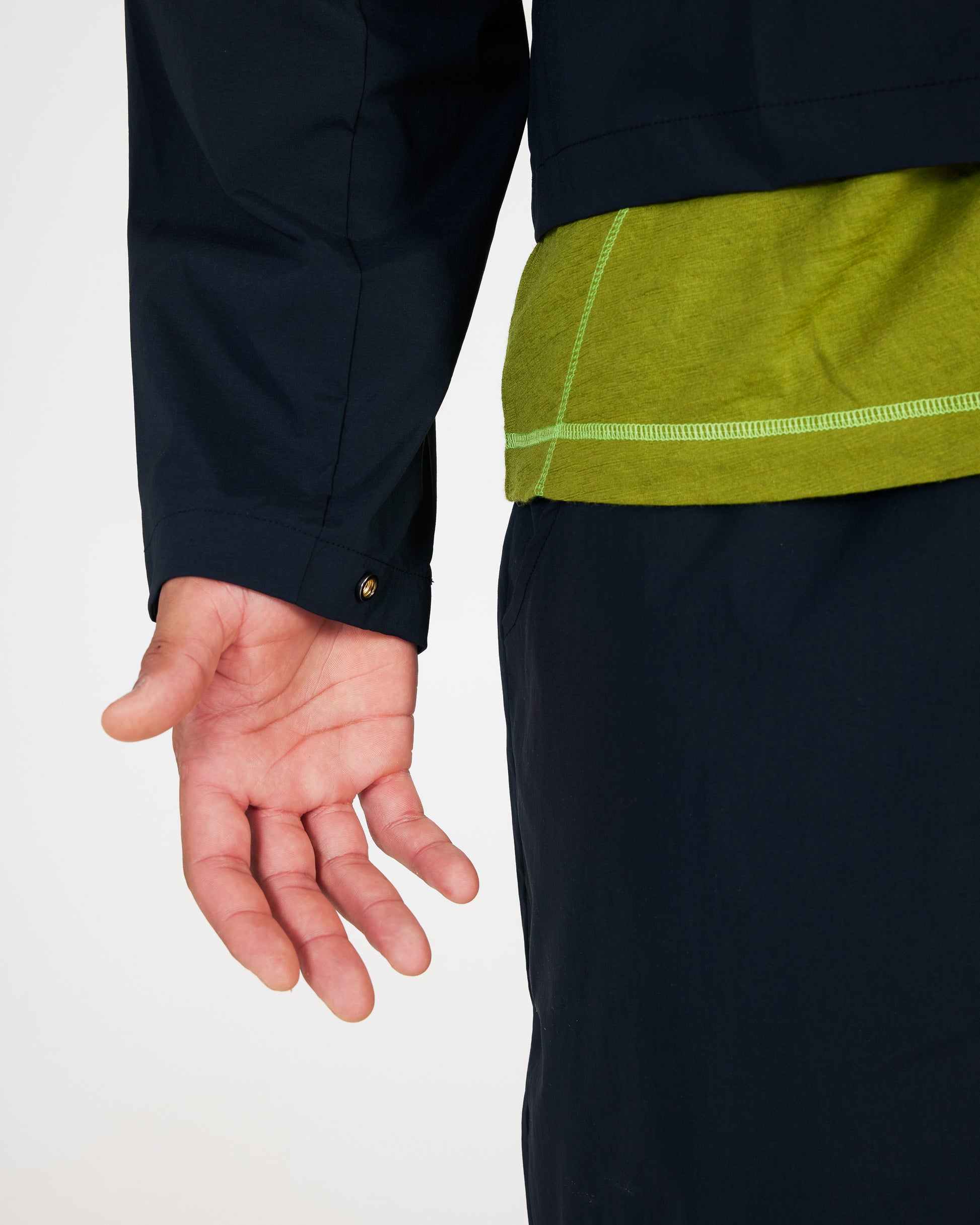 Close-up of a person wearing a dark jacket with green lining on a white background