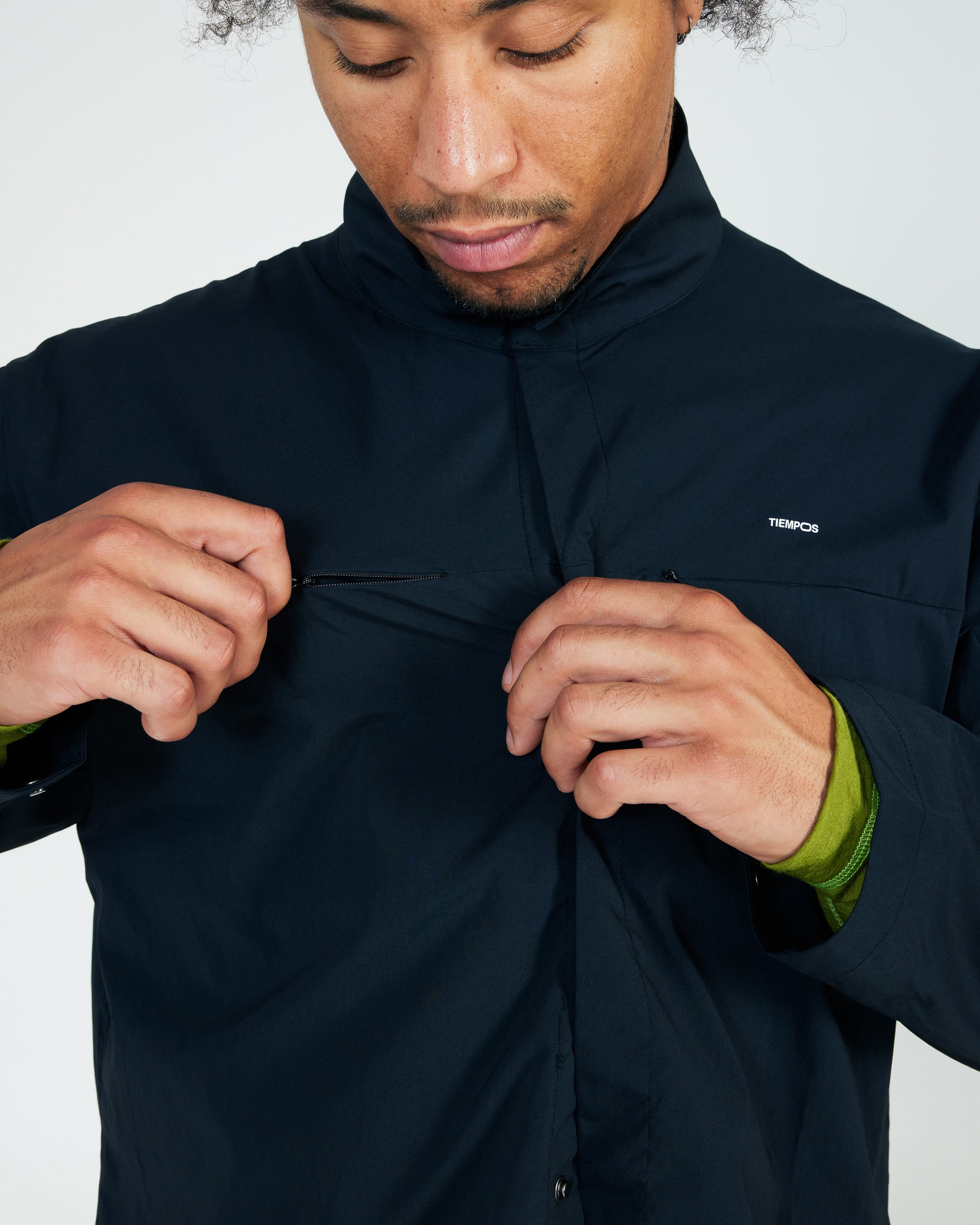 Person wearing a black jacket with a brand logo on a light gray background