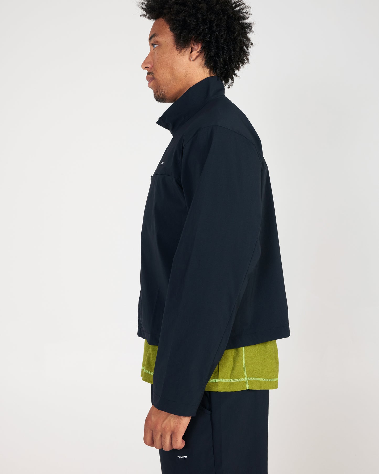 Man wearing a dark jacket over a light shirt with a white background