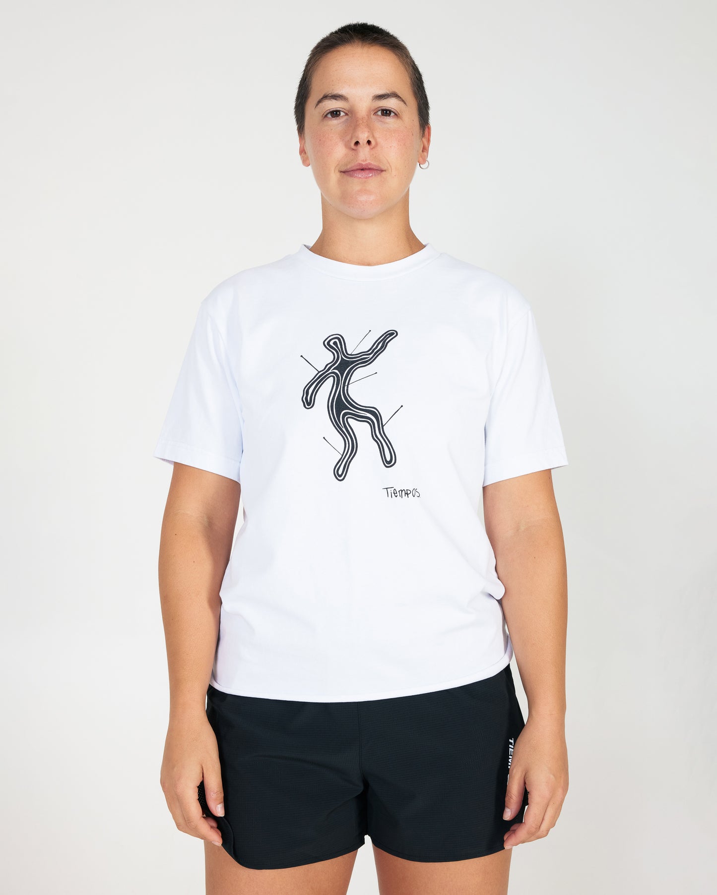 Person wearing a white t-shirt with a black graphic design on a plain background