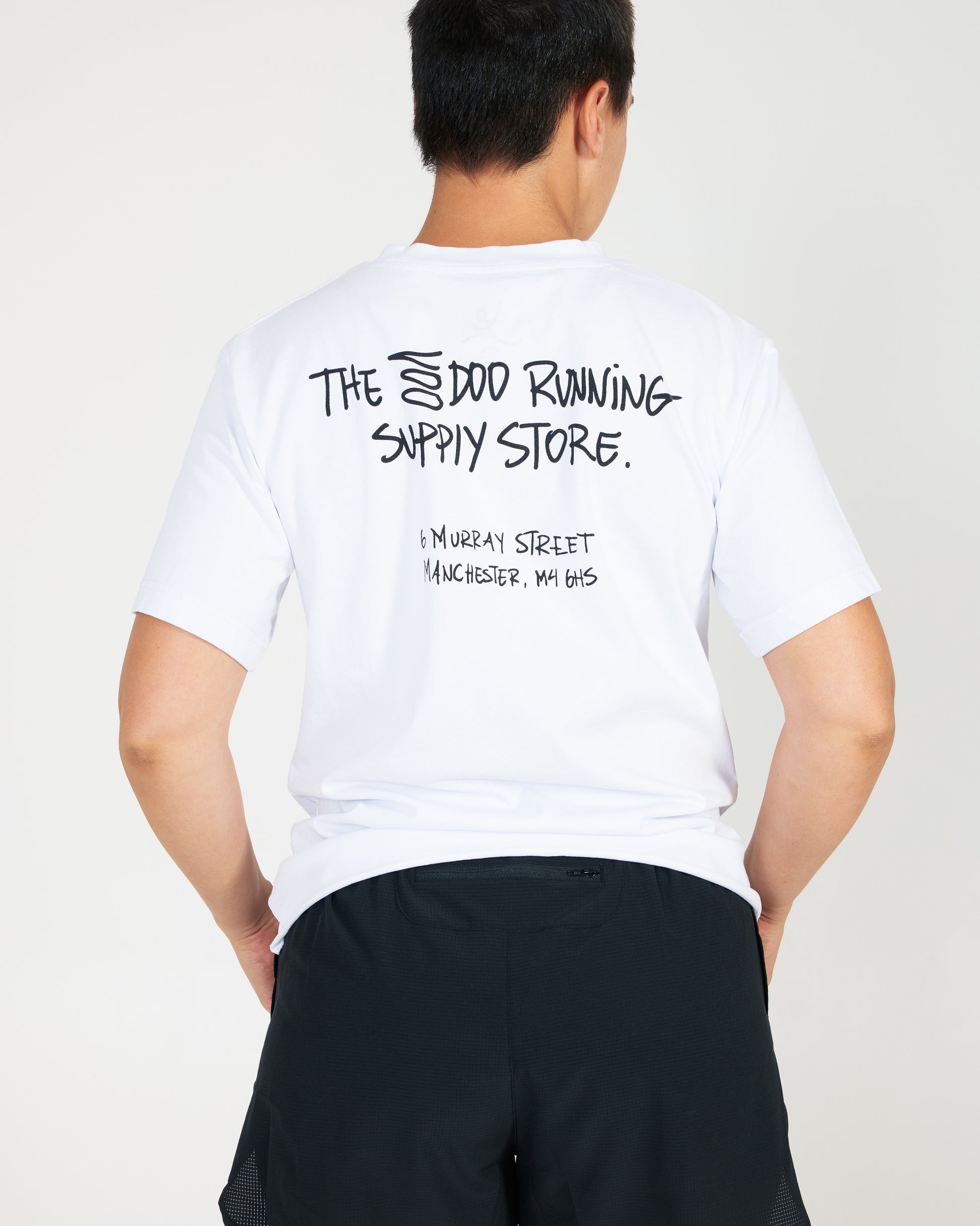 Person wearing a white t-shirt with text on the back against a plain background