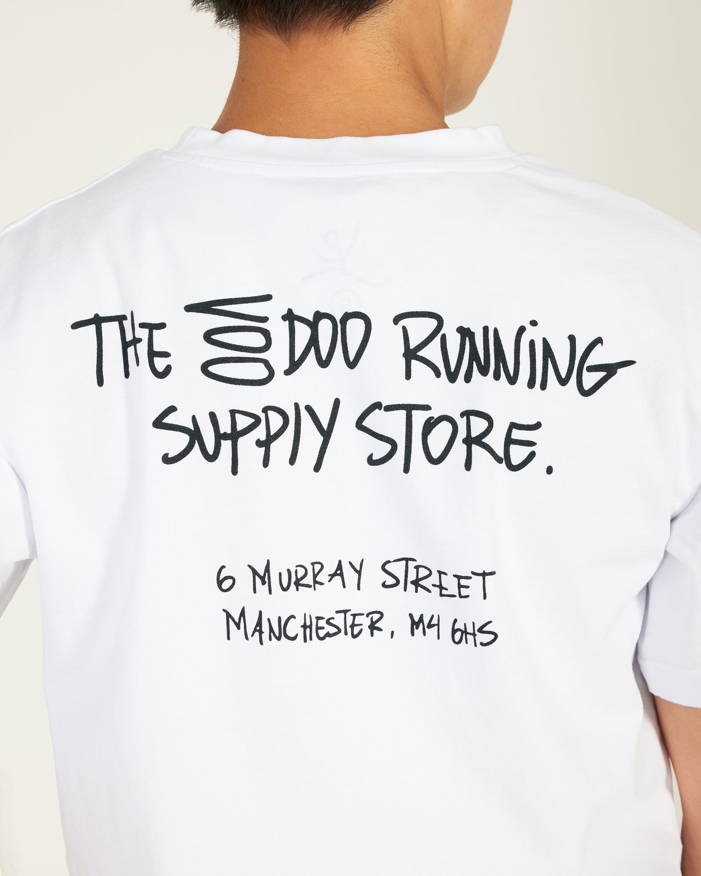 White t-shirt with black text on the back, featuring a store name and address.